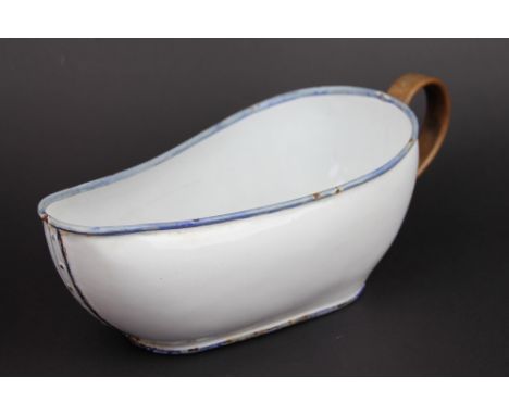 A 19th century French enamel bourdaloue, the bent wood handle with wood flower head rivets and faux rivet seams at sides, 29.