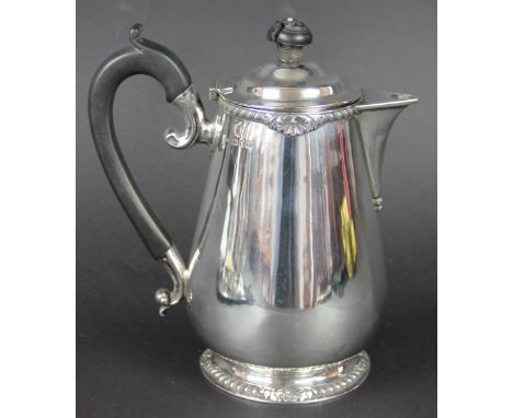 A silver hot water jug, Frazer & Haws, London 1927, of baluster shape and with gadrooned and shell borders, ebonised handle a