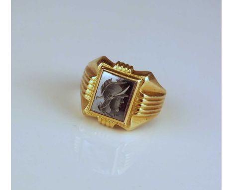 A Hematite signet ring, with engraved intaglio depicting a Centurion, mounted to tapering yellow metal shank stamped to the e