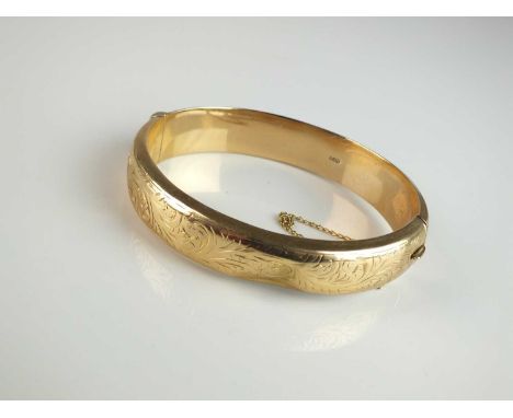 A 9ct gold hinged bangle, with bright cut engraved decoration, hallmarked Chester 1957, with attached safety chain, weight ap