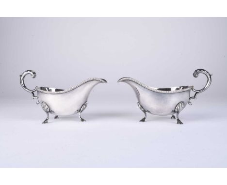 A pair of silver sauce boats by Harrods Ltd, Sheffield 1937, each of typical form with gadrooned rim and raised on three step