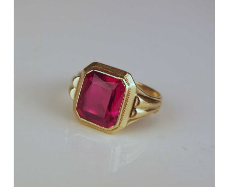 A Gentleman's synthetic ruby ring, the rectangular faceted synthetic ruby mounted to tapered shoulders, the yellow metal shan