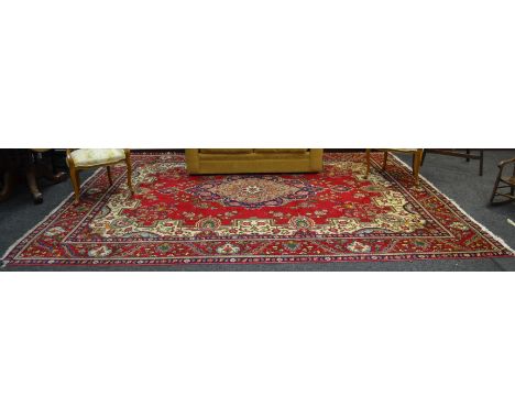 A Persian wool carpet, in tones of Imperial red, cream and blue, 300cm x 380cm 