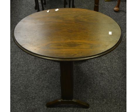 An early-20th Century oak oval tilt-top table, above magazine rack, c.1930; a set of three graduating tooled-leather inlaid c