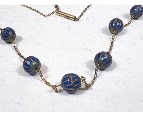 A yellow metal chain necklace with integral 7 blue enamelled beads, length 78cm. 
