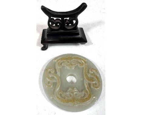 A Chinese jade coloured hardstone circle pendant on carved wooden stand, diameter 6cm 