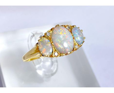 An 18 carat gold dress ring set large central opal flanked by 2 smaller opals and 4 small diamonds 