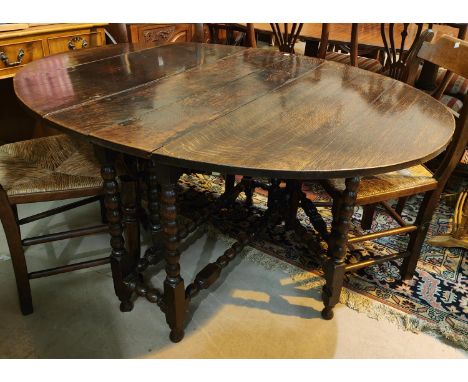 An 18th century oak dining table with oval top on bobbin turned gate legs 