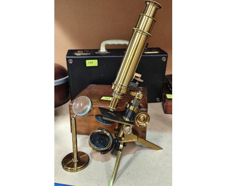 An early 20th century brass tripod microscope in a fitted wooden box. 