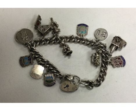 A heavy silver curb link charm bracelet decorated with numerous enamel and other charms. Approx. 51 grams. Est. £40 - £50.