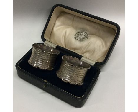 A cased pair of engine turned silver napkin rings of shaped forms. Birmingham 1919. Approx. 35 grams. Est. £35 - £40.