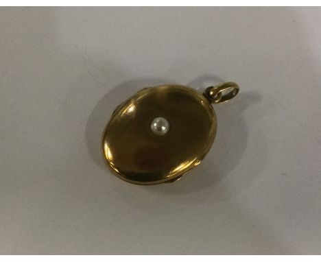 An oval pearl locket set in gold with loop top. Approx. 8 grams. Est. £60 - £80.