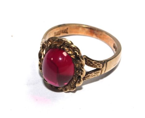 A 9 carat gold ring set with a red cabochon stone 