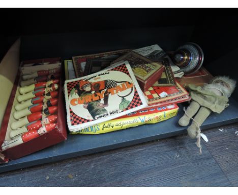 A shelf of vintage toys including Table Skittles, Tiddly Winks, Spinning Top and cloth doll