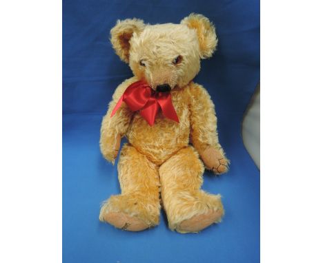 A mid 20th century straw filled yellow plush Merrythought teddy bear having glass eyes, stitched long nose and mouth and join