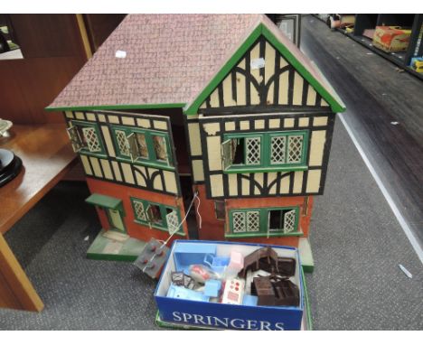 A vintage wooden two storey dolls house having tin plate windows and a selection of plastic and tin plate furniture and acces