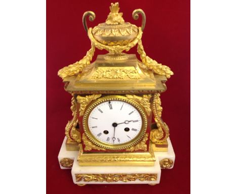 A Victorian ormolu & marble mantle clock, the architectural style case with swags surmounted by an urn, the enamelled dial wi