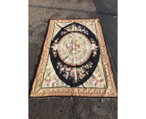 A French au basin style tapestry, with oval floral panel framed by black border, the spandrels with floral bouquets, the oute