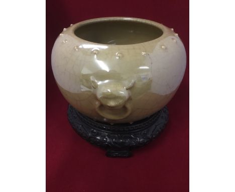 A Chinese stoneware bowl moulded with nipples and masque style ring handles, glazed in pale crackle brown, mounted on scroll 
