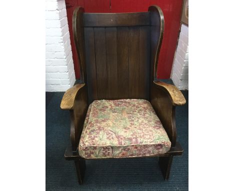 A porters style oak armchair of pegged construction with tongue & grooved back and loose cushion.