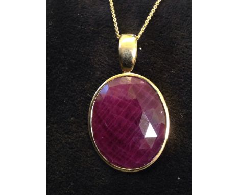 An 18ct hallmarked yellow gold mounted ruby pendant, the faceted oval bezel set ruby of over twenty-four carats, on a taperin
