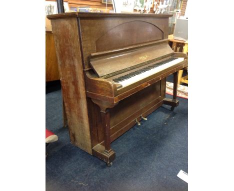 An oak cased upright piano by Spencer of London, the seven octave keyboard retailed by Murdoch & Co, the case with arched pan