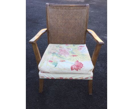 An Edwardian cane-backed chair with upholstered sprung seat and loose cushion, raised on sabre legs.