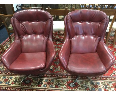 A pair of 60s egg style button upholstered armchairs with loose cushions, raised & swivelling on columns with five legs. (2)