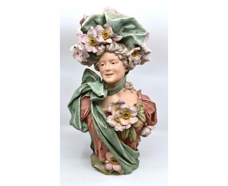 A good Royal Dux bust of a girl, circa 1908, modelled as a young woman of the period with solft bonnet applied with flowers, 