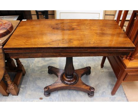 An early Victorian rosewood card table, with a fold-over top, raised on a reeded baluster turned column, standing on a platfo