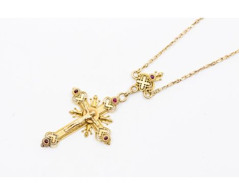 An ornate yellow metal crucifix, heart shaped decoration to each quarter with ruby set terminals, suspended from a decorative