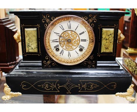 A French late 19th Century eight day black and gilt mantel clock with lions head, enamel and gilt face, Roman numerals