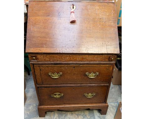 A Georgian oak bureau, of small proportions, the later replaced fall front enclosing drawers and pigeon holes, above two two 