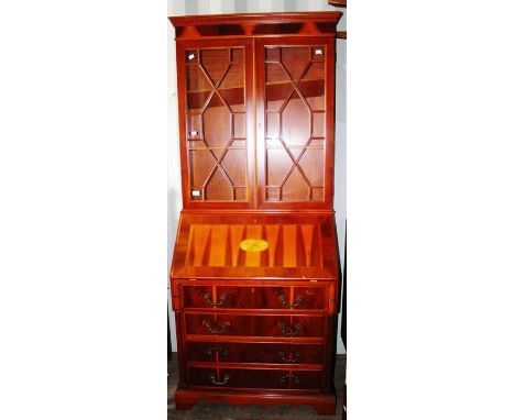 A Georgian style yew veneered bureau bookcase, fitted with two glazed doors, the fall front inlaid with a panel of inlay, fit