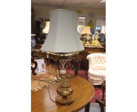 A reproduction mahogany table lamp with integral hour glass, modern, of turned onion form and applied with a brass plaque apo