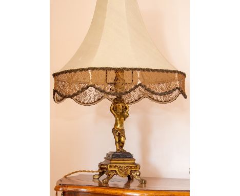 A reproduction French gilt metal figural table lamp, 20th Century, modelled as a putto standing with arms raised, set on a bl