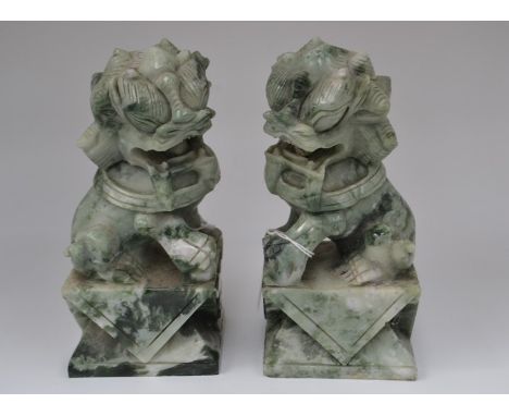 A pair of Chinese carved jade Dogs of Foe, each seated on a carved block plinth base, 20th Century, each measuring 20cm high 