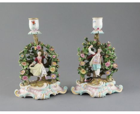 A pair of Meissen figural candlesticks, late 19th century, each modelled with a figure of either a lady or gentleman in a flo