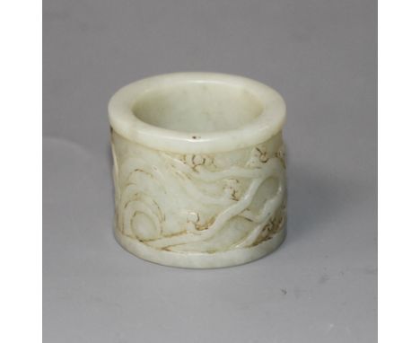 A Chinese pale celadon jade archer's ring, 17th/18th century, carved in relief with prunus and flowers, the stone of good eve