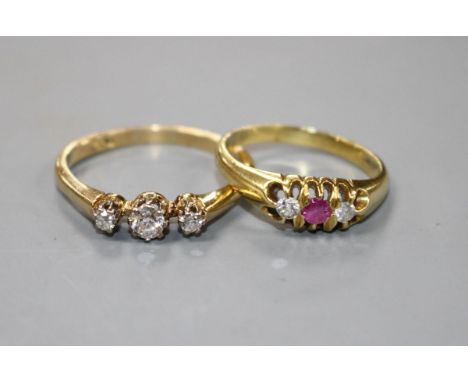 A modern 18ct gold, ruby and diamond set three stone ring and an 18ct and three stone diamond ring, sizes N &amp; T, gross we