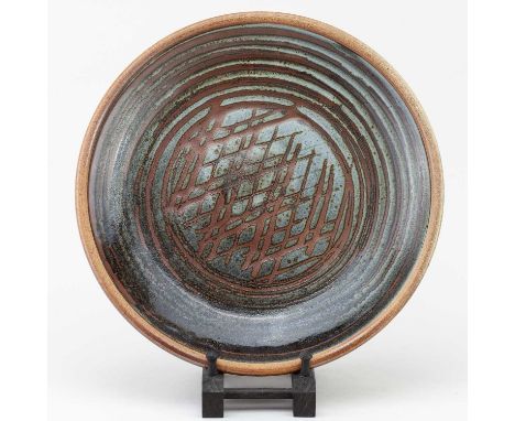 † JOHN LEACH (1939-2021) for Muchelney Pottery; a wood fired stoneware dish covered in mottled grey and tenmoku glaze with wa