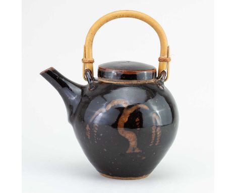 † DAVID LEACH (1911-2005) for Lowerdown Pottery; a stoneware teapot with cane handle covered in tenmoku breaking to kaki glaz