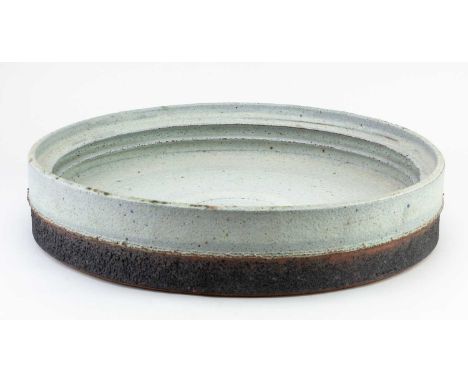 † ROBIN WELCH (1936-2019); a very large stoneware dish with internal flanges covered in pitted pale grey and bronze glaze, im