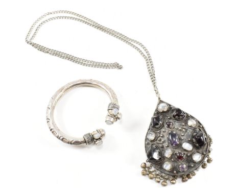 A gem set pendant necklace and torque bangle. The pendant being set with amethyst, moonstone and garnet cabochons. The bangle