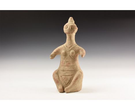An undated archaistic ceramic idol with incised lines to the body, discoid face with spike to the rear.   1.2 kg, 25cm (9 3/4