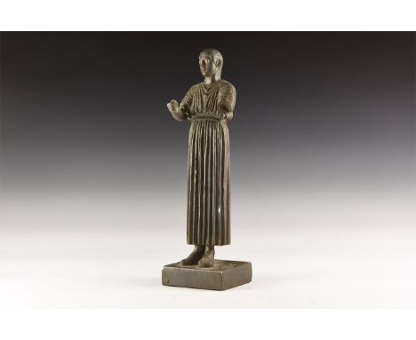 A ceramic undated archaistic statuette of the Charioteer of Delphi, wearing long robes to feet, belt at waist, right hand ext