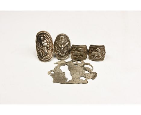 20th century AD. A mixed group of silver-coloured metal items comprising: a bifacial figural plaque; two finger rings with ad