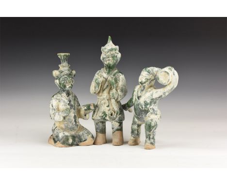20th century AD. A group of three ceramic green glazed statuettes of performers; one balancing plates to the head, one holdin