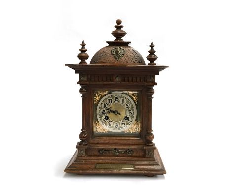 A German oak cased mantle clock by Junghams, the bevelled glass front flanked by a pair of pillars, the 11cm face with Arabic