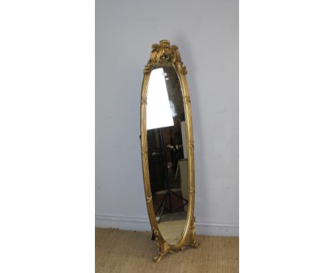 A reproduction oval gilt dressing mirror, of oval form with scrolled foliate crest and reeded frame and scrolled feet, easel 
